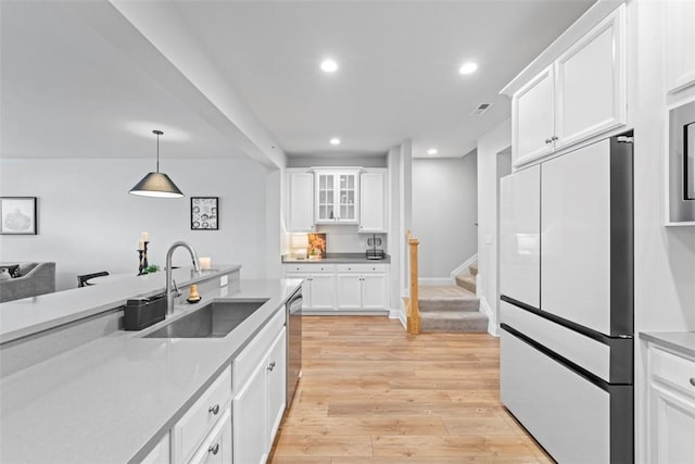 kitchen featuring white cabinetry, light countertops, a sink, and freestanding refrigerator