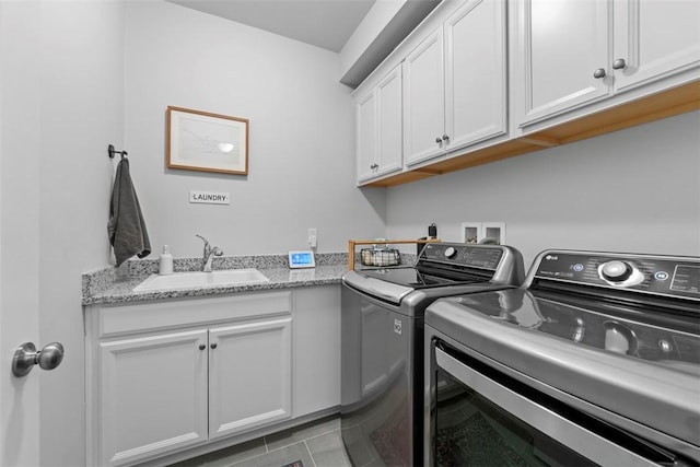 laundry area with cabinet space, light tile patterned floors, washer and clothes dryer, and a sink