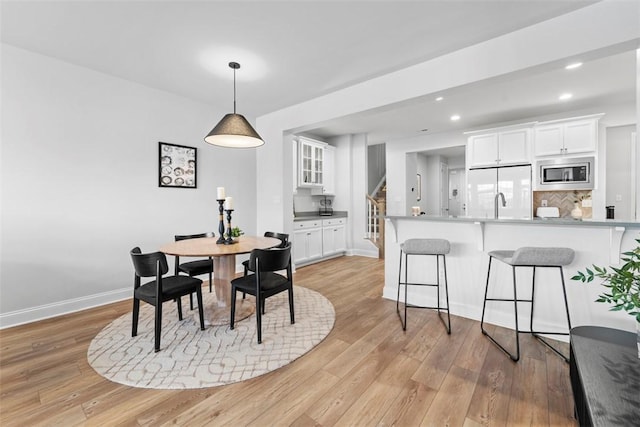 dining room featuring light wood finished floors, stairway, baseboards, and recessed lighting