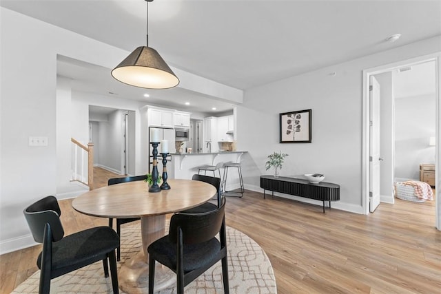 dining room with recessed lighting, light wood-style flooring, baseboards, and stairs