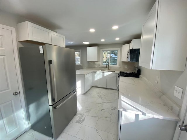 kitchen with white cabinetry, sink, backsplash, light stone counters, and stainless steel appliances