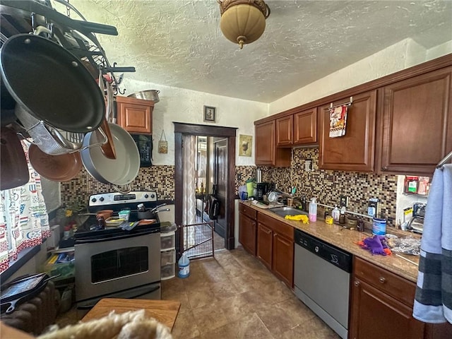 kitchen with sink, light stone counters, tasteful backsplash, a textured ceiling, and appliances with stainless steel finishes