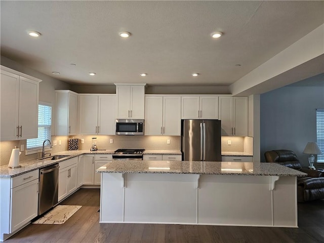 kitchen with stainless steel appliances, a center island, sink, and white cabinets