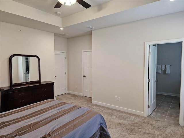 bedroom featuring ensuite bathroom, light carpet, ceiling fan, and a tray ceiling