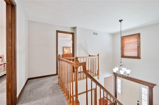 hall featuring a wealth of natural light, light carpet, and a notable chandelier