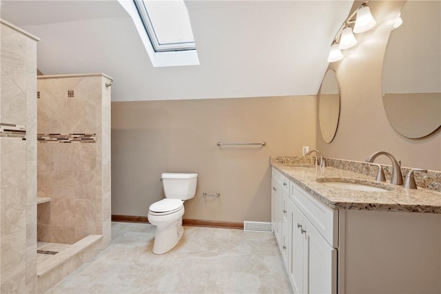 bathroom featuring vanity, toilet, vaulted ceiling with skylight, and a tile shower