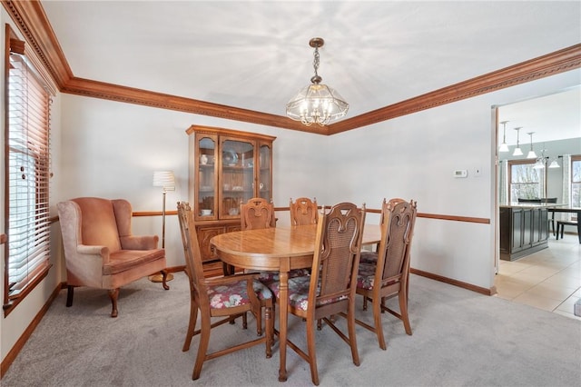 carpeted dining space with crown molding and an inviting chandelier