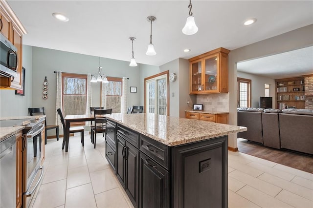 kitchen with light stone countertops, appliances with stainless steel finishes, a center island, and pendant lighting