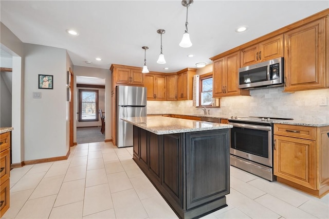 kitchen featuring pendant lighting, light stone counters, stainless steel appliances, and a center island