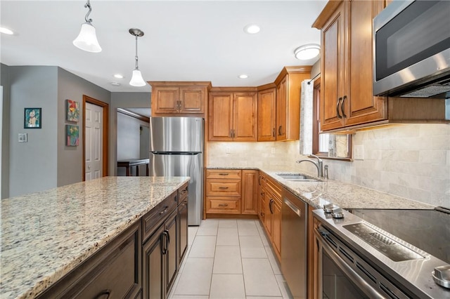 kitchen with sink, backsplash, stainless steel appliances, light stone counters, and decorative light fixtures