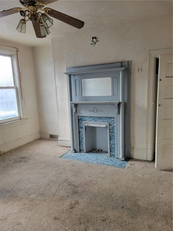 unfurnished living room with ceiling fan, light carpet, and a fireplace