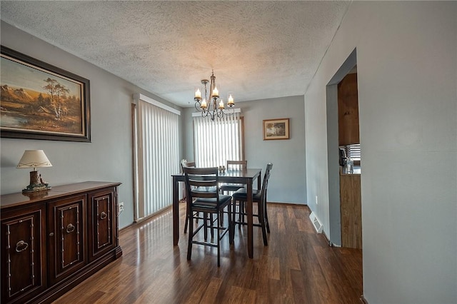 dining area with a notable chandelier, dark hardwood / wood-style floors, and a textured ceiling