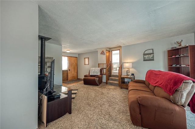 carpeted living room with a wood stove and a textured ceiling