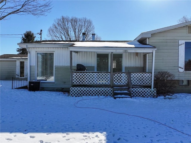 snow covered rear of property featuring covered porch