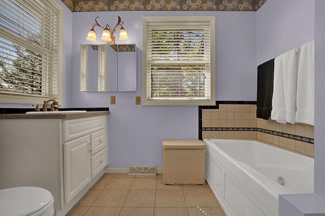 bathroom featuring tile patterned flooring, vanity, a washtub, and toilet