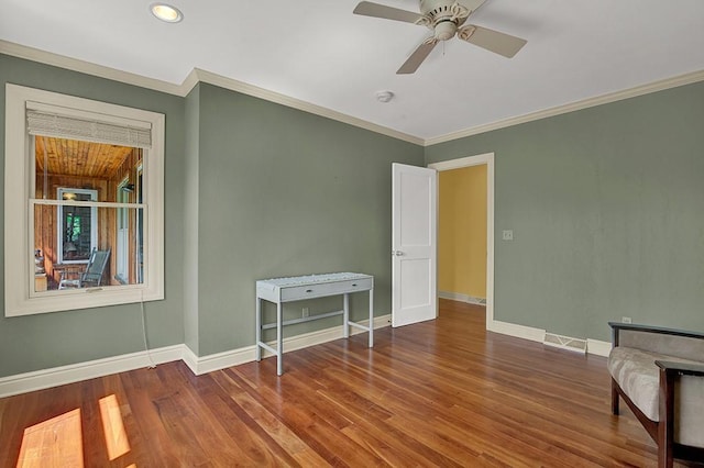 empty room featuring crown molding, wood-type flooring, and ceiling fan