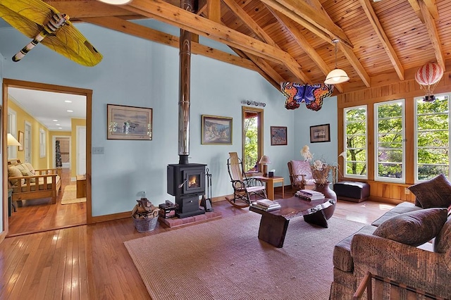 living room featuring high vaulted ceiling, wooden ceiling, a wood stove, beamed ceiling, and light hardwood / wood-style floors