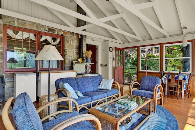 sunroom with vaulted ceiling with beams, plenty of natural light, and a wood stove