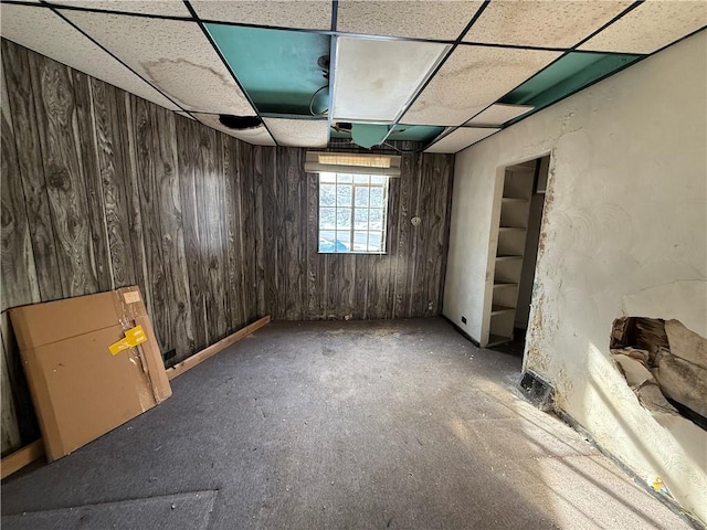 basement with wooden walls and a drop ceiling