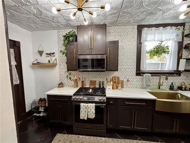 kitchen with appliances with stainless steel finishes, dark tile patterned flooring, sink, and dark brown cabinets