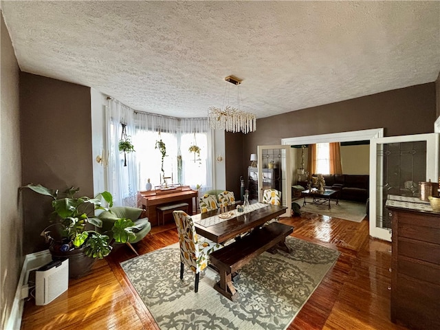 dining area with wood-type flooring, a wealth of natural light, and a textured ceiling