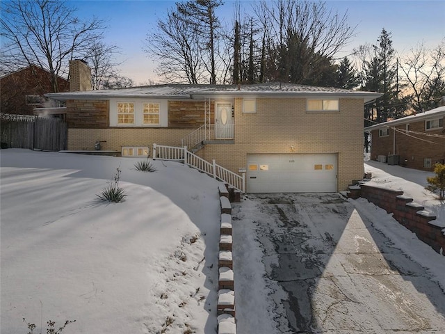 snow covered house featuring a garage