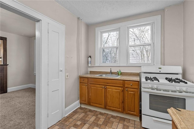 kitchen featuring sink, white range with gas stovetop, and a textured ceiling