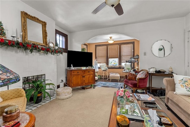 living room with a tile fireplace, ceiling fan, and carpet flooring