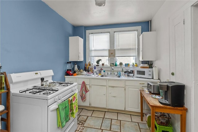 kitchen with white appliances, sink, and white cabinets