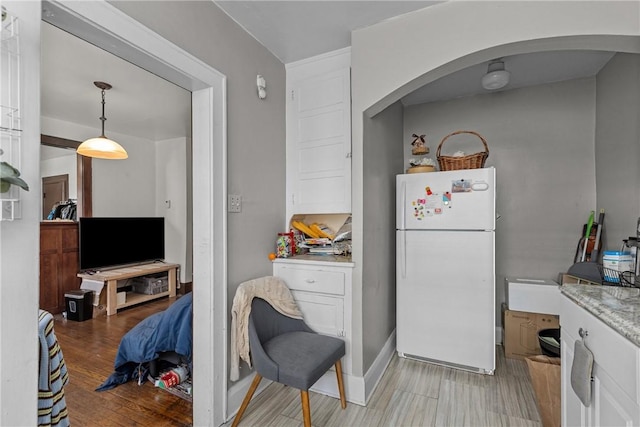 kitchen with decorative light fixtures, light hardwood / wood-style floors, white cabinets, and white fridge