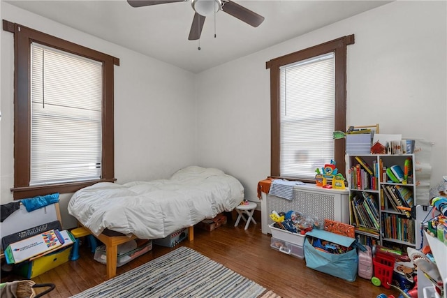 bedroom featuring ceiling fan, dark hardwood / wood-style floors, and multiple windows