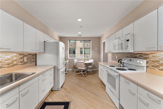 kitchen featuring sink, white appliances, white cabinetry, light hardwood / wood-style floors, and decorative backsplash