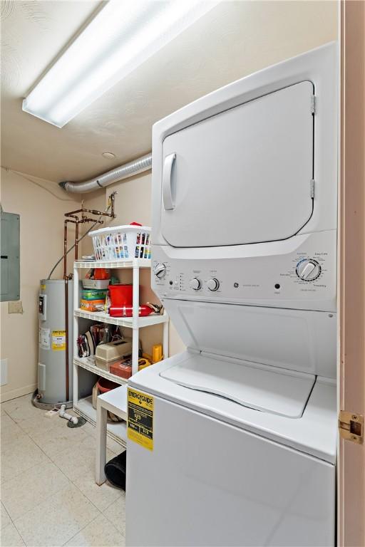 washroom with stacked washer and dryer, electric panel, and electric water heater