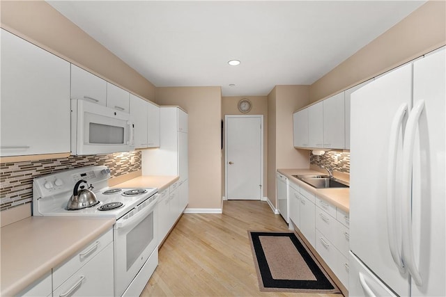 kitchen featuring sink, white cabinetry, light hardwood / wood-style flooring, white appliances, and decorative backsplash