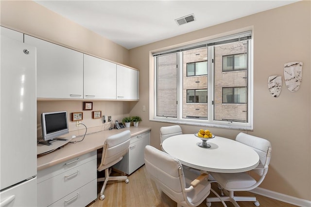 home office with built in desk and light hardwood / wood-style flooring