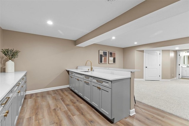 kitchen featuring gray cabinets, sink, light hardwood / wood-style floors, and kitchen peninsula