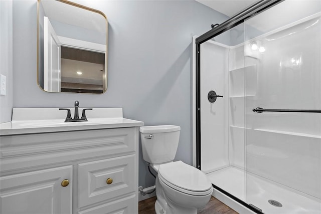 bathroom with vanity, hardwood / wood-style floors, a shower with shower door, and toilet