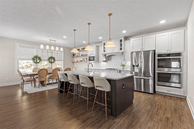 kitchen featuring stainless steel appliances, hanging light fixtures, white cabinets, and light stone counters