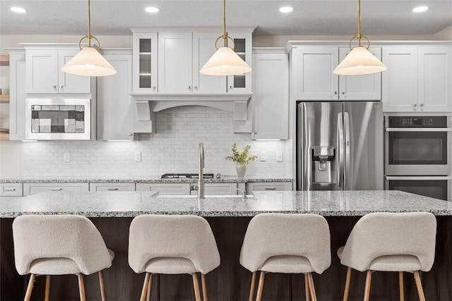 kitchen featuring decorative backsplash, an island with sink, white cabinets, and appliances with stainless steel finishes