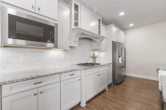 kitchen with white cabinetry, appliances with stainless steel finishes, dark hardwood / wood-style flooring, and light stone counters