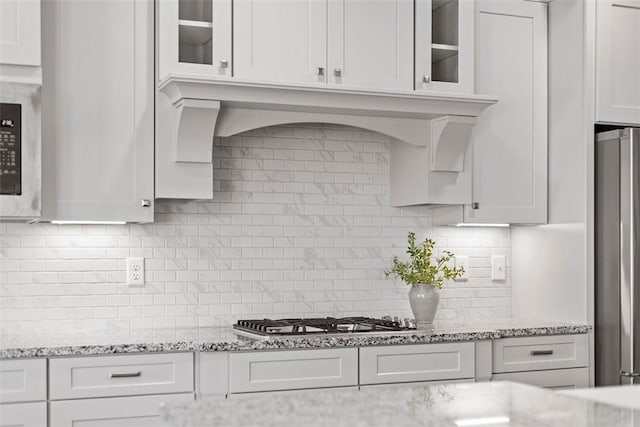 kitchen featuring tasteful backsplash, stainless steel appliances, light stone countertops, and white cabinets