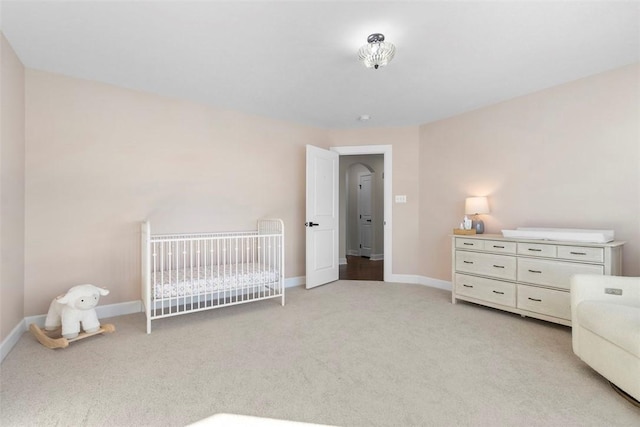 bedroom featuring light carpet and a nursery area