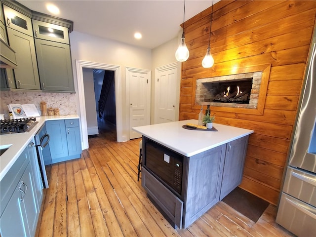 kitchen featuring decorative light fixtures, light hardwood / wood-style floors, a center island, and appliances with stainless steel finishes