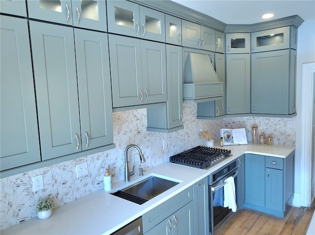 kitchen with decorative backsplash, stainless steel appliances, sink, and custom range hood