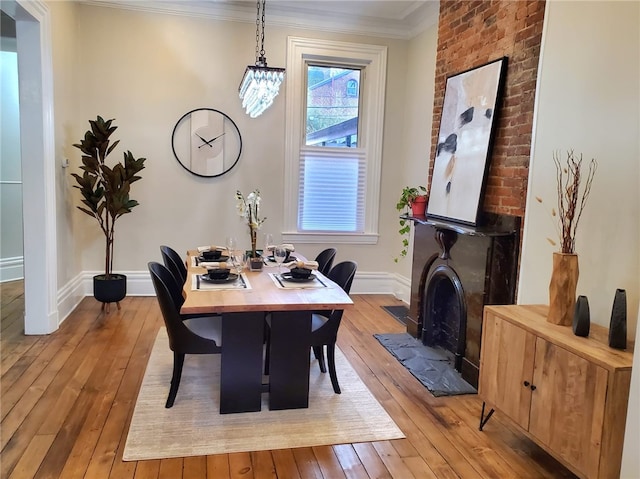 dining room with ornamental molding, light hardwood / wood-style floors, and a large fireplace