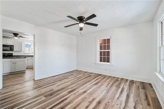 unfurnished room with ceiling fan, a textured ceiling, and light hardwood / wood-style flooring