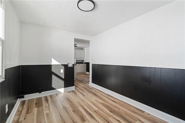 unfurnished room featuring light wood-type flooring and a textured ceiling