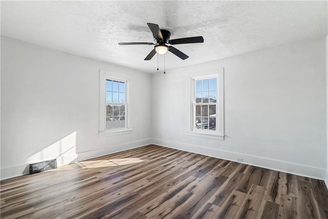 spare room with ceiling fan, a wealth of natural light, a textured ceiling, and dark hardwood / wood-style flooring