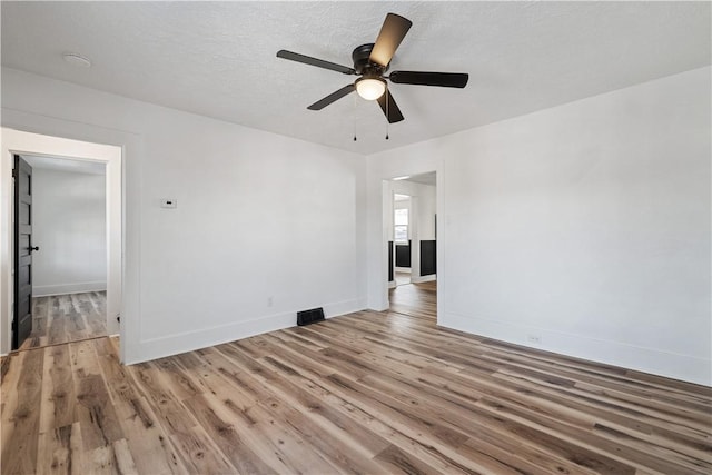 unfurnished room featuring ceiling fan, hardwood / wood-style floors, and a textured ceiling