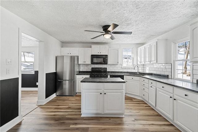 kitchen with sink, white cabinets, stainless steel fridge, stove, and a center island